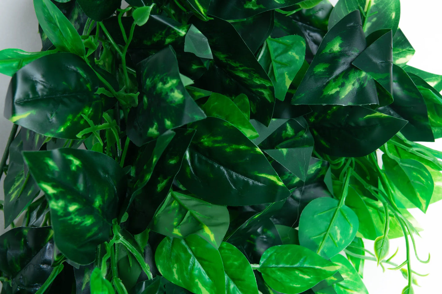 Detalle follaje artificial colgante de hojas verdes de 90 cm con mezcla de hojas en diferentes tonalidades de verde, ideal para decorar eventos, pérgolas, muros verdes e interiores.
