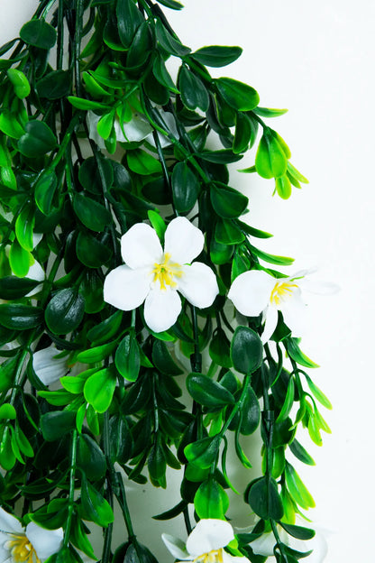 Detalle guirnalda colgante artificial con follaje verde y flores blancas, ideal para decorar bodas, eventos, arcos florales, techos y espacios interiores.