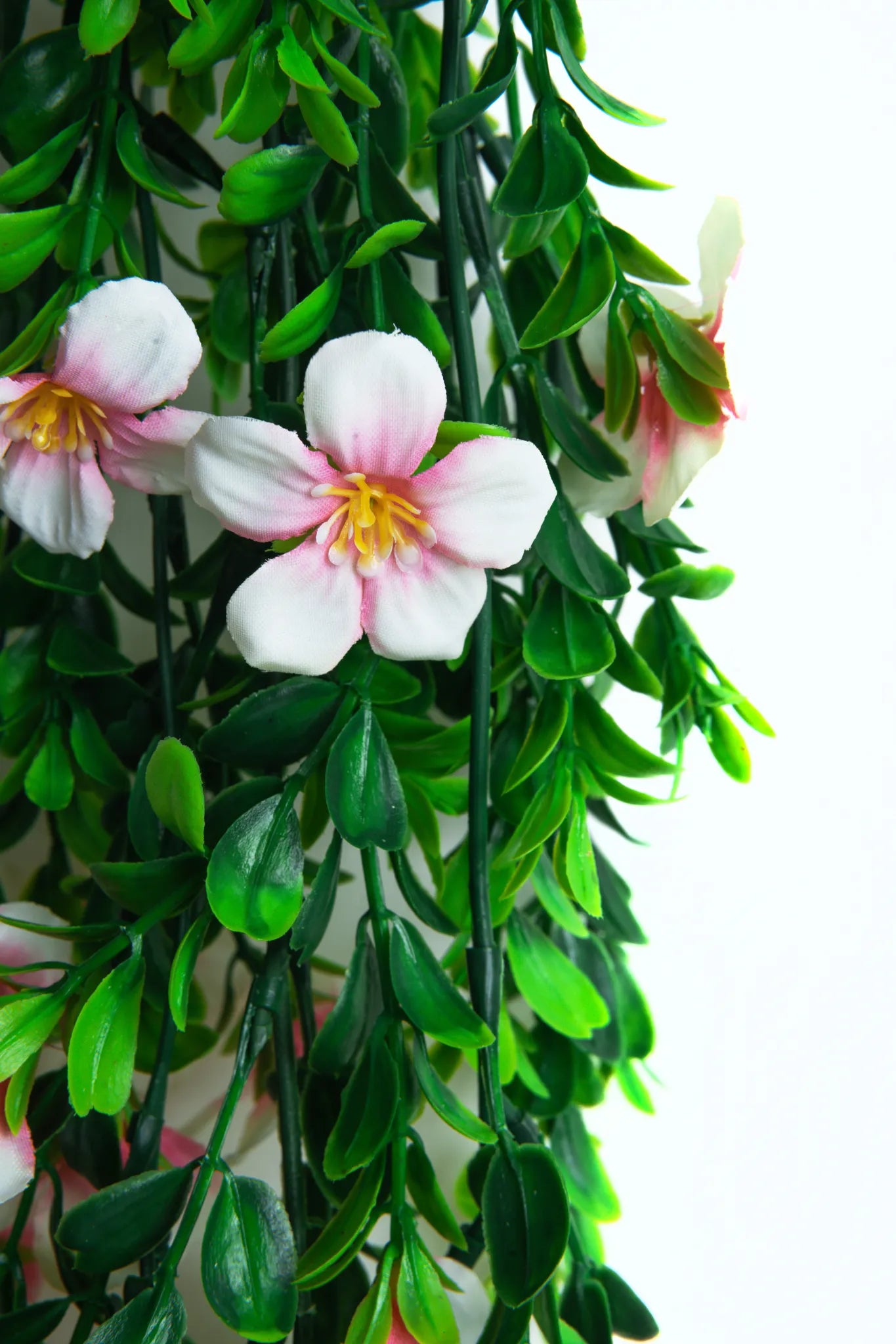 Detalle guirnalda colgante artificial con follaje verde y flores color rosa claro, ideal para decorar bodas, eventos, arcos florales, techos y espacios interiores.