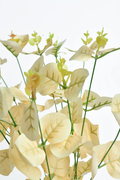 Detalle rama de eucalipto artificial color crema con hojas redondeadas y brotes verdes, ideal para arreglos florales, centros de mesa, bodas, eventos y decoración de interiores.