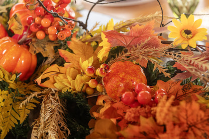 Centro de mesa decorado con picks artificiales de girasol, frutos otoñales, calabazas y follaje en tonos cálidos para decoración de otoño.