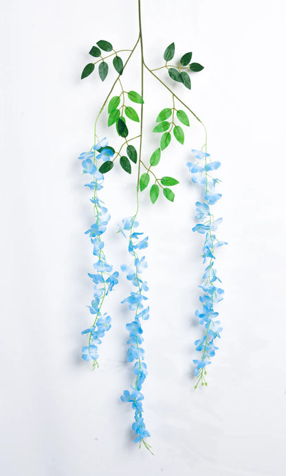 Guirnalda colgante artificial de wisteria azul con hojas verdes y flores en cascada, ideal para decorar bodas, eventos, pérgolas, arcos florales y espacios interiores.