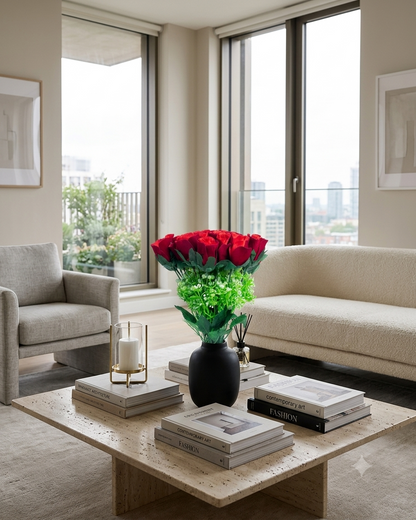 Ramo artificial de rosas rojas colocado en un florero negro sobre una mesa de centro en una sala moderna con iluminación natural, ideal para decorar interiores.